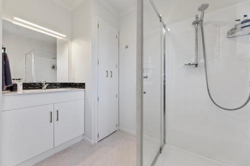 a white bathroom with a shower and a sink at Knightsbridge Court Motor Lodge in Blenheim