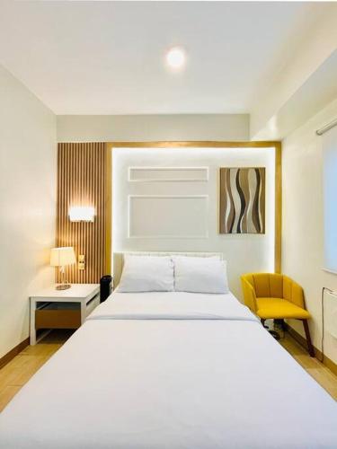 une chambre avec un grand lit blanc et une chaise jaune dans l'établissement 18 Warm Studio Oasis, à Cari Mayor