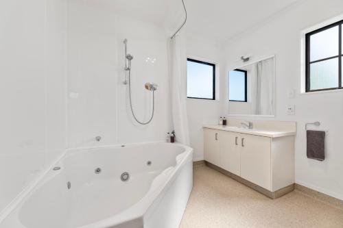 a white bathroom with a tub and a sink at Knightsbridge Court Motor Lodge in Blenheim