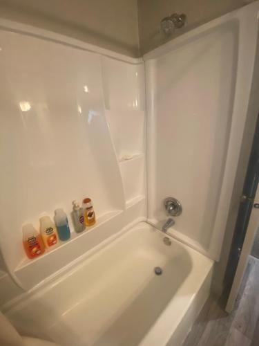 a white bath tub in a white bathroom with bottles at Entire Tiny House with Large Yard Fenced In! in West Valley City