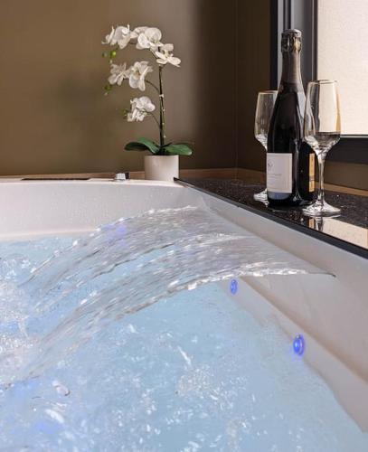 - une baignoire remplie d'eau à côté d'une bouteille de vin dans l'établissement Les Suites du Payré - Suite Passion, à Talmont-Saint-Hilaire