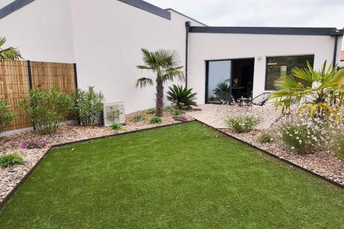 einen Garten mit grünem Rasen vor einem Haus in der Unterkunft Les Suites du Payré - Suite Passion in Talmont
