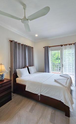 a bedroom with a large bed with a ceiling fan at Sanssouci Kep in Kep