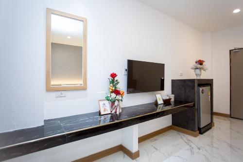 a room with a counter with a television and flowers at One Sakon Nakhon Hotel in Ban Na Weng