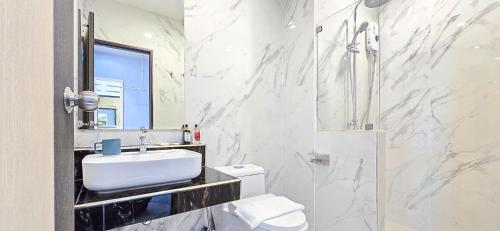 a white bathroom with a sink and a toilet at One Sakon Nakhon Hotel in Ban Na Weng