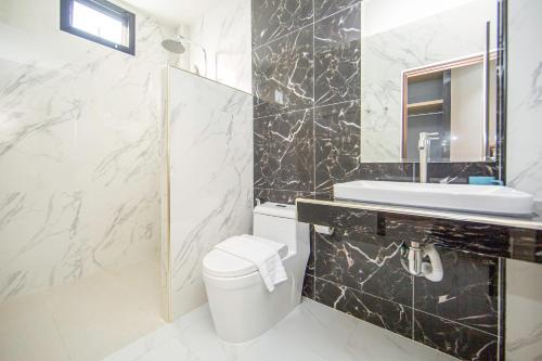 a bathroom with a toilet and a sink and a mirror at One Sakon Nakhon Hotel in Ban Na Weng