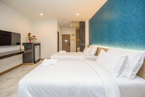 a bedroom with two white beds and a blue wall at One Sakon Nakhon Hotel in Ban Na Weng