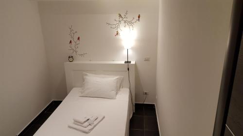 a small bedroom with a white bed with a light on it at Hotel Ascot in Caianello
