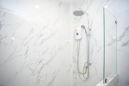 a bathroom with a shower with white marble walls at One Sakon Nakhon Hotel in Ban Na Weng