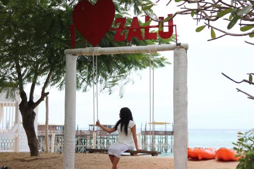 a woman sitting on a swing on the beach at Essque Zalu Zanzibar in Nungwi