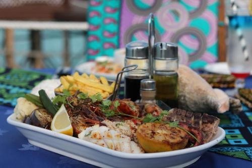 a plate of food with seafood and french fries on a table at Essque Zalu Zanzibar in Nungwi
