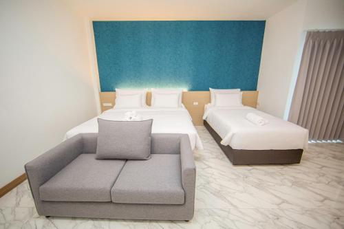 a hotel room with two beds and a couch at One Sakon Nakhon Hotel in Ban Na Weng