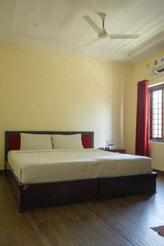 a bedroom with a large bed with a ceiling fan at Ghala Tourist Home in Cochin