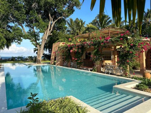 a swimming pool in front of a house with flowers at Al Mahali Villas Diani Beach in Diani Beach