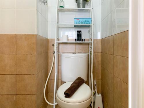 a bathroom with a toilet with a shelf above it at Modern Look and Comfortable 2BR Green Pramuka City Apartment By Travelio in Jakarta