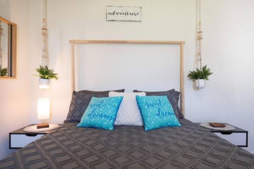 ein Schlafzimmer mit einem Bett mit zwei blauen Kissen in der Unterkunft Cali 2BR Getaway Firepit, Yard & Spring Charm in Tucson