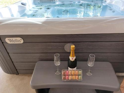 a bottle of champagne and two glasses on a table in a bathtub at gîtes gorevirat in Corcelles