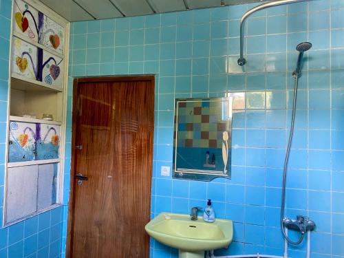 a blue tiled bathroom with a sink and a mirror at Vanadzor Family Art House in Vanadzor