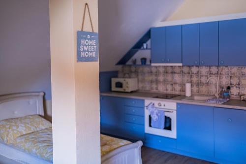 a kitchen with blue cabinets and a sign that says have a sweet house at Penzion Benátky in Pelhřimov