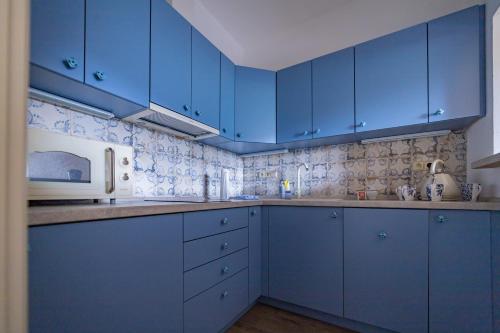 a blue kitchen with blue cabinets and a microwave at Penzion Benátky in Pelhřimov