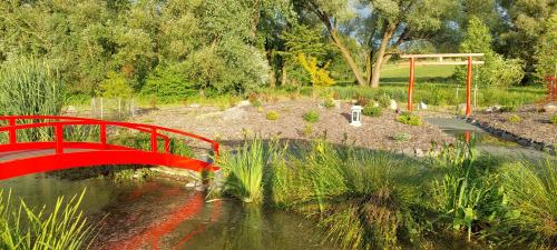 a red bridge over a pond in a garden at Tópart Apartmanok in Nagylengyel