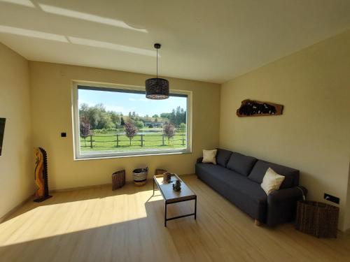 a living room with a couch and a large window at Tópart Apartmanok in Nagylengyel