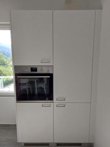 a white kitchen with white cabinets and an oven at gîtes gorevirat in Corcelles