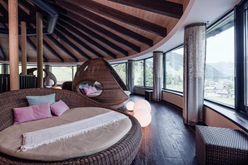 a bedroom with a wicker bed in a room with windows at Familienresort Ellmauhof - das echte All Inclusive in Saalbach Hinterglemm