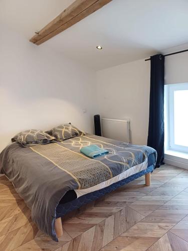a bed in a white room with a wooden floor at T3 le caoulet, 3 pers, 3lits, wifi, climatisation in Foulayronnes