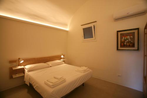 a bedroom with a bed with white sheets and towels at Il Carrubo in Procida