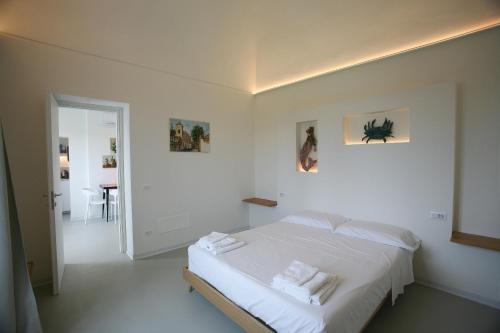 a white bedroom with a bed with white sheets at Il Carrubo in Procida
