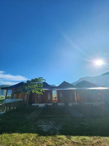 a house with the sun shining behind it at Punik family syariah in Sembalun Lawang