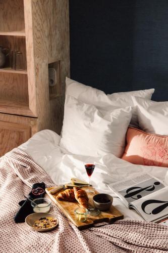 a tray of food and a glass of wine on a bed at Libertine Lindenberg in Frankfurt/Main