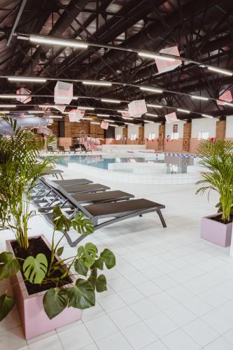 a swimming pool with plants and benches in a building at Cukrownia Żnin in Żnin