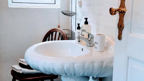 a bathroom with a white sink and a chair at Store Ejlstrup Bed & Breakfast in Odense