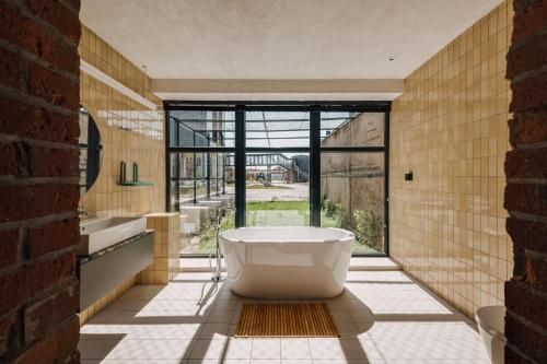 a bathroom with a tub and sinks and a large window at Cukrownia Żnin in Żnin
