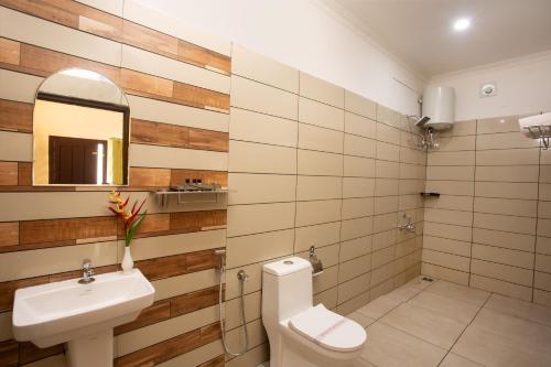 a bathroom with a sink and a toilet and a mirror at The Arbour Resort Munnar in Munnar