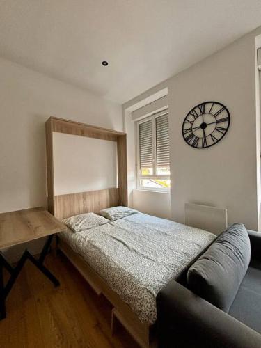 une chambre avec un lit et une horloge au mur dans l'établissement Studio fonctionnel, centre ville, rénové 205, à Saint-Étienne
