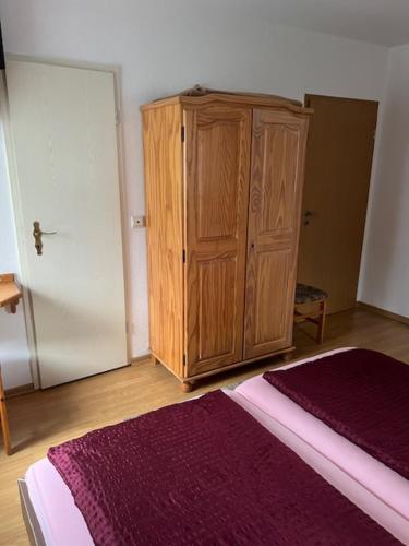 a bedroom with a wooden cabinet and a bed at Gästehaus Elisabeth Bach in Mehring