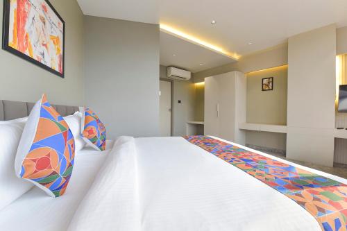 a bedroom with a white bed with colorful pillows at FabHotel Prime The Grey Circle in Indore