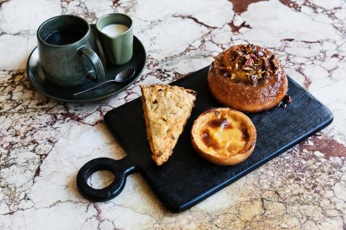 a black plate with a pastry and a cup of coffee at Downtown Los Angeles Proper Hotel, a Member of Design Hotels in Los Angeles