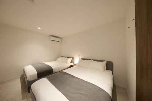 two beds in a room with white walls at Nanki Shirahama Villa IRIS in Kanayama