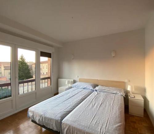 a bedroom with a large bed and a large window at Sego Apartments III in Segovia