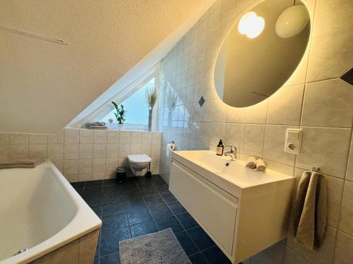 a bathroom with a sink and a tub and a toilet at Sälzer Apartment in Bad Sassendorf