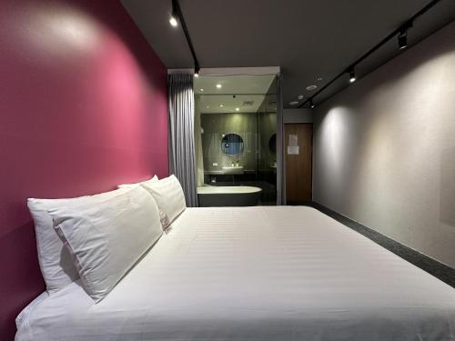 a bedroom with a large bed with a pink wall at Cho Hotel 3 in Taipei
