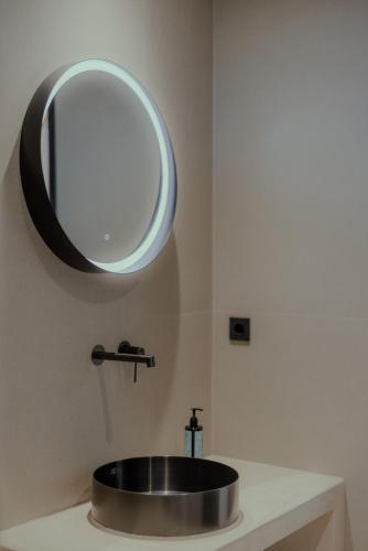 a bathroom sink with a round mirror on the wall at NIAMA Luxury apartments Nafplio in Nafplio