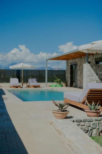a swimming pool with two lounge chairs and a house at NIAMA Luxury apartments Nafplio in Nafplio