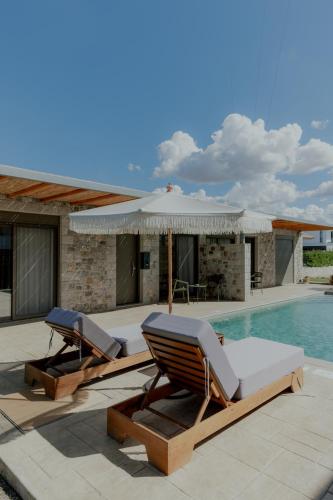two lounge chairs and an umbrella next to a swimming pool at NIAMA Luxury apartments Nafplio in Nafplio
