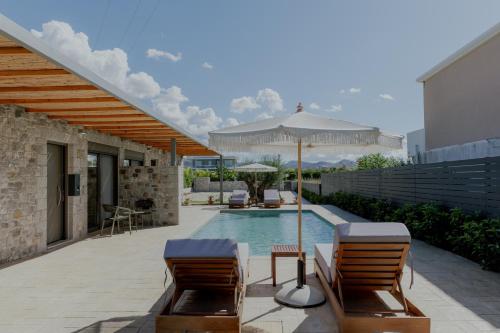 a swimming pool with two chairs and an umbrella at NIAMA Luxury apartments Nafplio in Nafplio