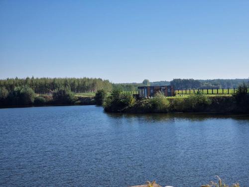 a view of a river with a house in the distance at GRETA Nowoczesny domek modułowy nad stawem in Jodłowiec